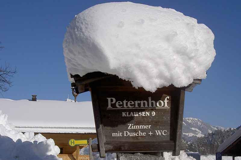 Holzschild mit Schneehaube vor dem Peternhof in Kirchberg in Tirol